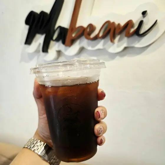 An iced americano in front of the Mabeani sign